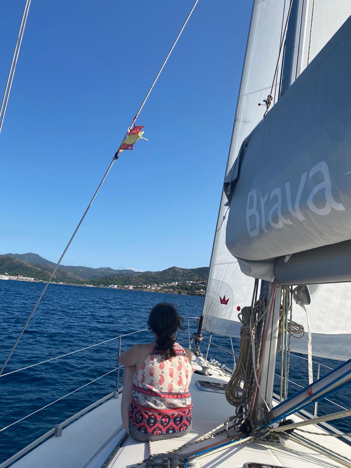 Chica navegando en la proa del velero en la costa Brava