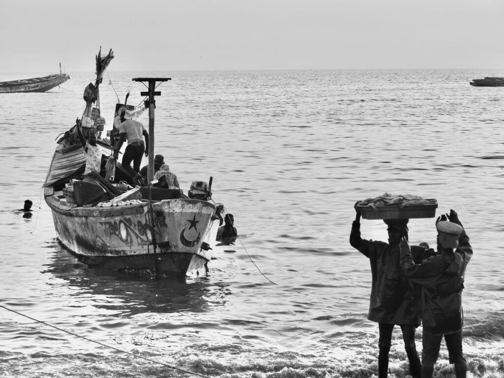 Porteadores y barcos en la costa de Mbour