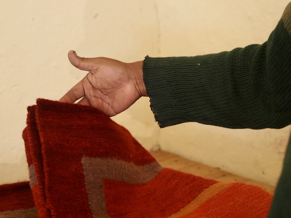 La mano de Guiso y una de sus alfombras de lana